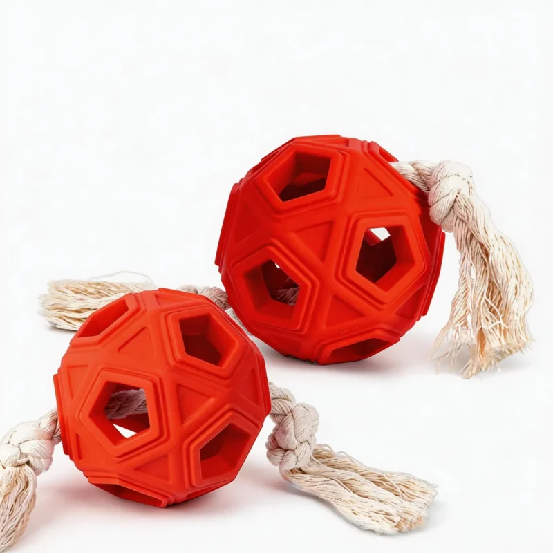 BriteTug Rope Dog Chew Ball shown as red rubber tug toys with geometric chew openings and knotted cotton rope ends on a white background.