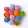 Tuxedo cat playing with Soft Yarn Pom Pom Silent Cat Toy Balls 6 Pack, soft 4 cm quiet balls for indoor cats