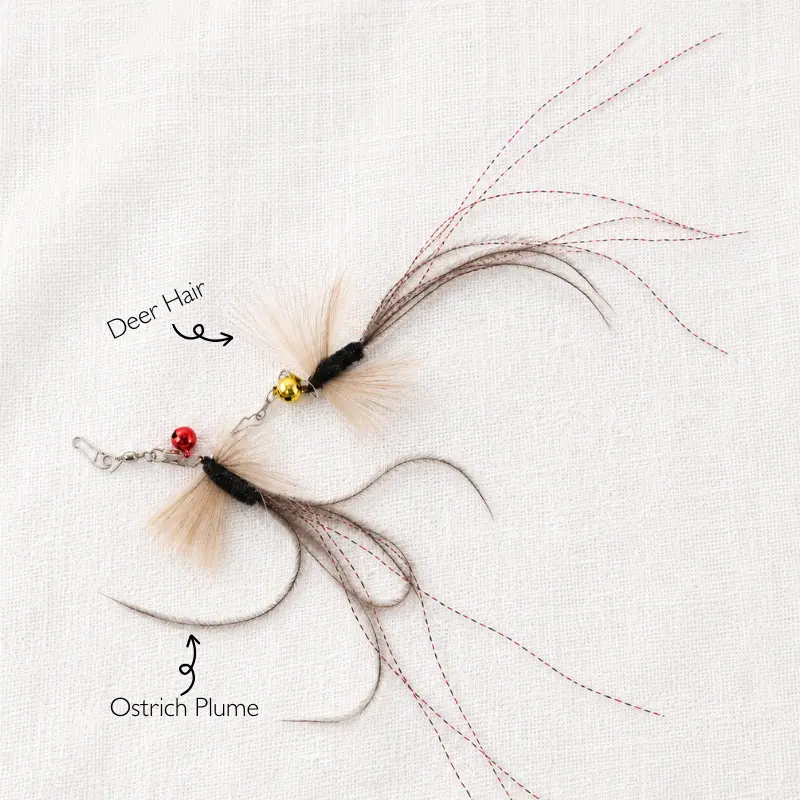 Two black flying insect cat wand attachments showing deer hair, soft ostrich plume, red tinsel, bells, and stainless steel snap clasps.