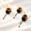 bumble-bee-cat-teaser-toy-natural-flying-prey-play-scene Handmade bumble bee cat teaser toy with fluffy body and fluttering wings shown in a natural outdoor scene for playful hunting style interaction.