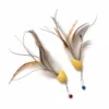 Close-up of two feather cat toy replacement lures with bright yellow bodies, layered feather tentacles, metal clip connectors, and red and blue bells.