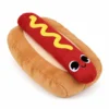 A cute dog plushie shaped like a hot dog, with a red sausage, yellow mustard stripe, tan bun, and embroidered smiling face.
