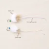 jellyfish-rabbit-fur-wand-toy-materials Two Jellyfish Rabit Fur wand toys for kittens showing white rabbit fur, deer hair, colored bells, and long iridescent ribbon-like streamers.