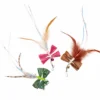 Three Raffia Flutter Bug wand toys for cats in pink, green and brown, with raffia wings, undyed feathers, iridescent tails, bells and clip connectors.