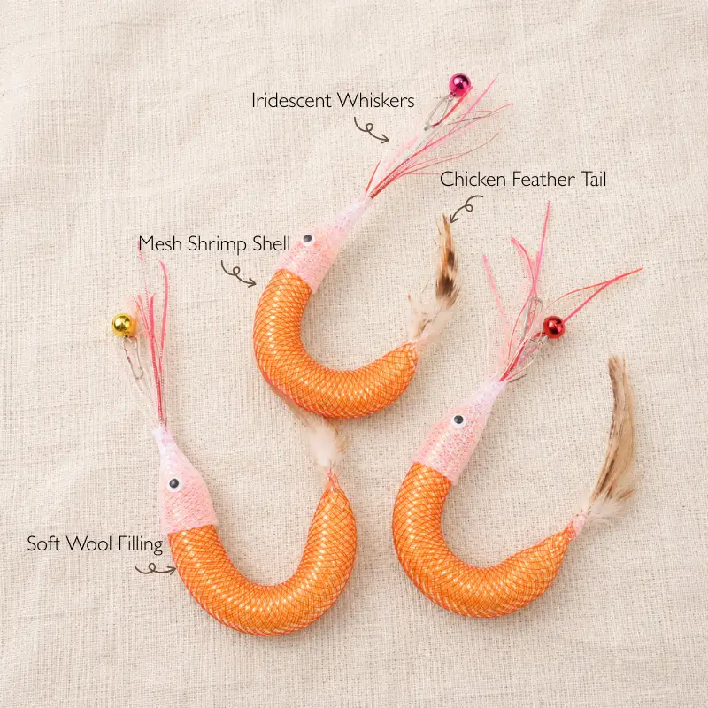 Material details of a handmade shrimp cat toy wand refill showing mesh shrimp shell, soft wool filling, chicken feather tail, and iridescent whiskers.