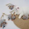 White cat resting beside Tiny Mouse Hunt Plush Cat Toy, a soft mouse-shaped toy for indoor cats to chase, bite, and carry