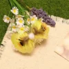 Yellow butterfly cat teaser beside white flowers, showing broad yellow wings, brown inner feathers, a soft pom body, and long antennae.