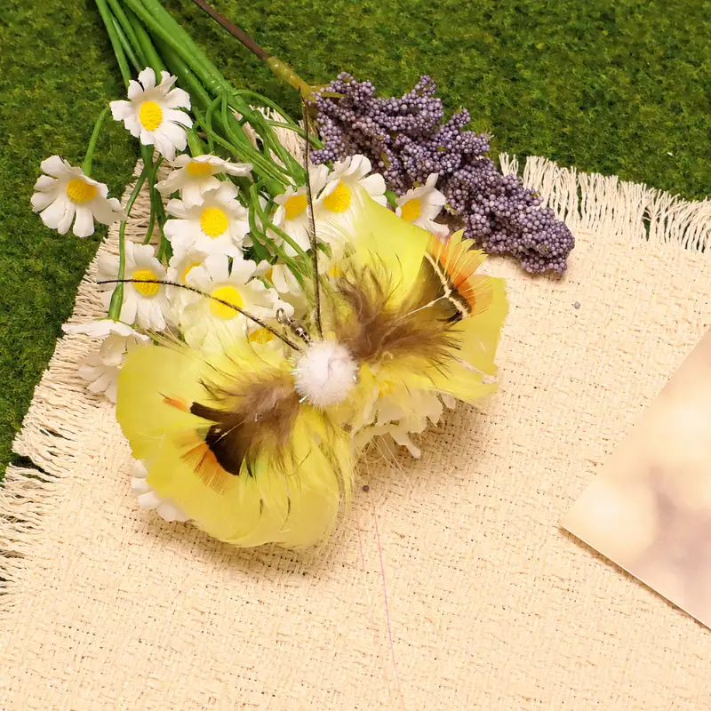 Yellow butterfly cat teaser beside white flowers, showing broad yellow wings, brown inner feathers, a soft pom body, and long antennae.