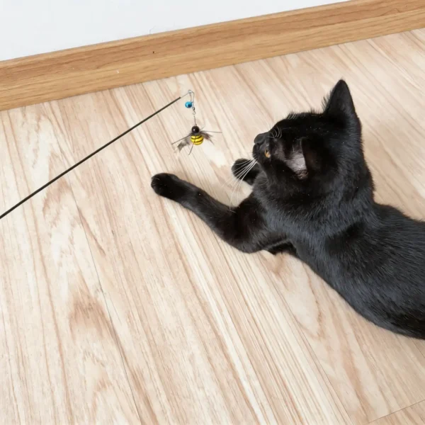 Black cat reaching for the BuzzBee Flutter Feather Cat Wand Replacement during indoor interactive play on a wooden floor.
