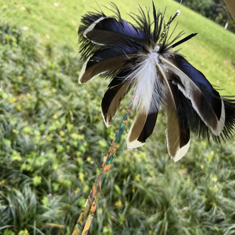giant-moth-cat-toy-feather-detail Close-up of a giant moth cat toy feather attachment with dark layered natural feathers, fluffy wing edges, and shimmering iridescent strips.