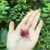 red-feather-crawling-ant-cat-toy-wand-outdoor Red feather crawling ant cat toy wand attachment displayed outdoors, showing its lightweight insect shape for engaging cat play.