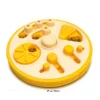 A yellow Busy Bites Dog Enrichment Puzzle Feeder with hidden kibble compartments, sliding pieces, and a 27 cm / 10.6 in size guide.