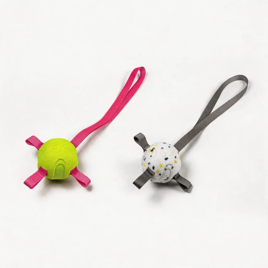 Two soft-bite ETPU dog fetch balls with straps on a white background, shown in White with Gray Strap and Lime with Pink Strap.