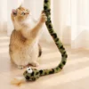 Cat pawing a green snake cat toy with long plush body for interactive grabbing and wrestling play.