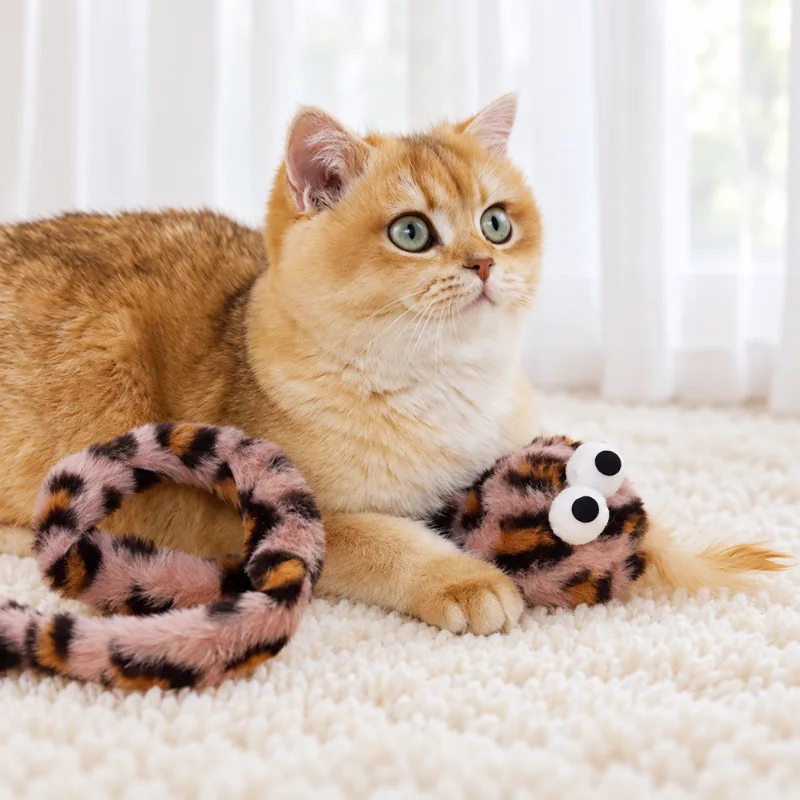 Cat playing with a pink leopard snake cat toy designed for grabbing, hugging, and bunny kick cat play.