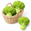 broccoli-plush-dog-toys-basket-display Three cute dog plushies shaped like smiling broccoli sit in and beside a wicker basket; these green squeaky plush dog toys have textured crowns.