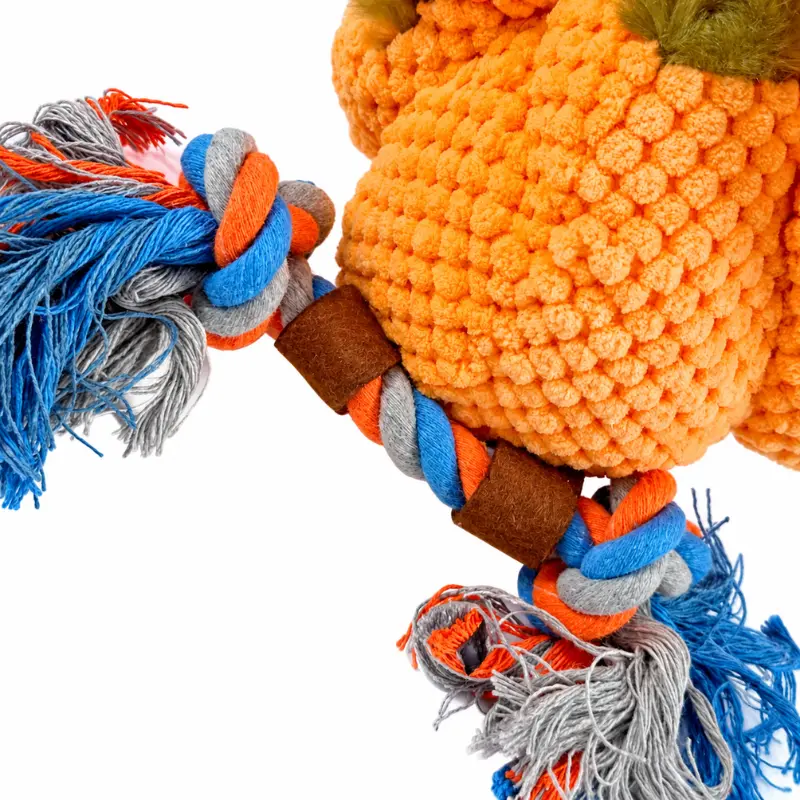 Close-up of colorful blue, orange, and gray cotton rope knots and tassels attached to the chicken stuffed toy's orange, nubby-textured plush body.