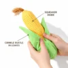 corn-plush-squeaker-crinkle-leaves Hands squeeze a corn-shaped plush squeaky dog toy, highlighting the squeaker inside the yellow cob and crinkle paper inside the green leaves.
