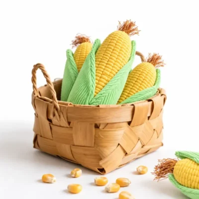 Several cute corn plush toys for dogs arranged in a woven basket, showing their golden cobs, green husks, and tassel details.