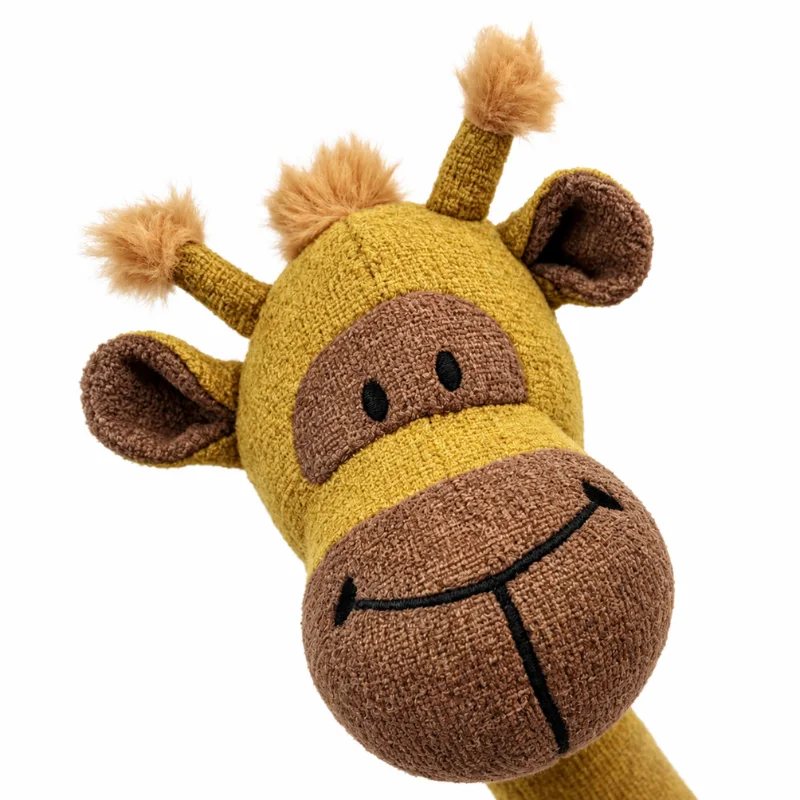 Close-up of the giraffe plush face, showing its brown muzzle, stitched smile, black eyes, ears, and textured mustard-yellow fabric.