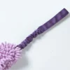 Close-up of the purple nylon webbing, stitching, and gathered elastic section of a dog tug of war toy with handle, beside the lavender chenille body.