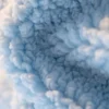 Close-up of the curly blue fabric on a cute dog plush, showing its raised, looped texture and fluffy surface.